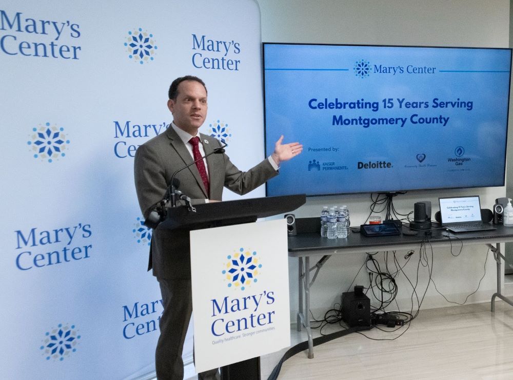 理事會主席格拉斯在以瑪麗中心標誌為背景的講台上發表講話。